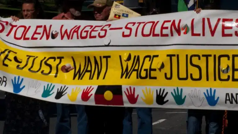 Image of protest banner saying 'stolen wages stolen lives, we just want wage justice'